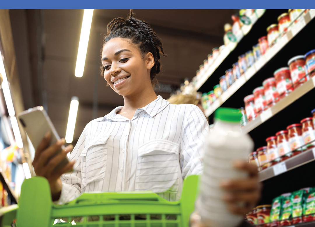 Woman using smartphone in grocery store while shopping